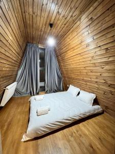 a bedroom with a bed in a wooden wall at Gudauri Sikhaura in Kʼumlistsʼikhe