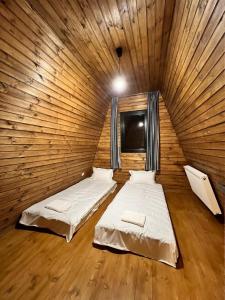 two beds in a room with a wooden wall at Gudauri Sikhaura in Kʼumlistsʼikhe