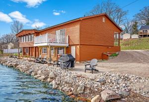 a large wooden house next to a body of water at 2 Units on Fife Lake with Hot Tub-Sleeps 14 in Fife Lake