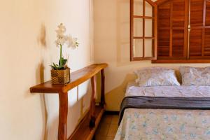 a bedroom with a bed and a table with flowers on it at Kefi Chalés - Vale do Capão in Palmeiras