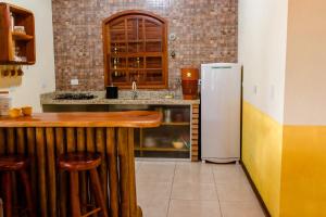 a kitchen with a counter and a refrigerator at Kefi Chalés - Vale do Capão in Palmeiras
