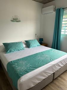 een groot bed met blauwe kussens in een slaapkamer bij Pension Irivai appartement "Uparu" 1 chambre bord de mer in Uturoa