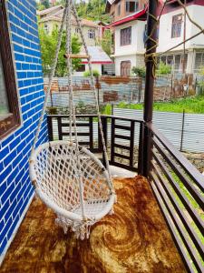 un columpio blanco sentado en un porche con vistas en POP Misba Homestay, en Bhadarwāh