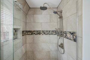 baño con ducha y puerta de cristal en Old Harbor Inn en South Haven