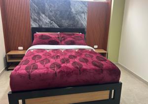 a bed with a red comforter and red pillows at Hotel Colonial House in Pasto