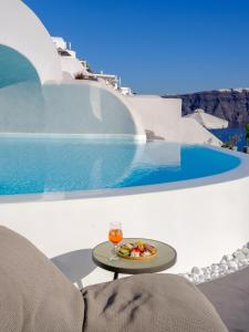 a table with a plate of food next to a pool at Nostos Apartments in Oia