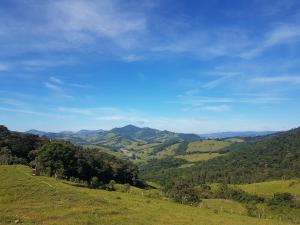 einen grünen Hügel mit Bäumen und Bergen in der Ferne in der Unterkunft Casa Nas Montanhas em Camanducaia Sul de Minas in Camanducaia