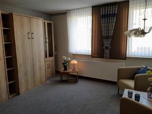 ein Wohnzimmer mit einem Sofa, einem Tisch und 2 Fenstern in der Unterkunft Haus Lieberum Apartment Erdgeschoß in Bad Sooden-Allendorf