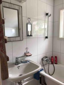 ein Badezimmer mit einem Waschbecken, einem Spiegel und einer Badewanne in der Unterkunft Reinefjorden Lodge in Reine