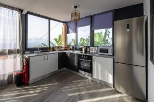 a kitchen with stainless steel appliances and large windows at Panoramic House in Quinta do Almeida