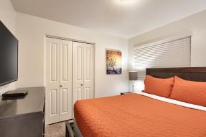 Cette chambre comprend un lit avec un couvre-lit orange et un bureau. dans l'établissement 6A Family Friendly RedCliff Condo POOL & HOT TUB (Pet Friendly), à Moab