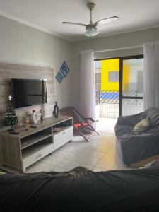 ein Wohnzimmer mit einem TV und einem Sofa in der Unterkunft Apartamento beira mar Centro da cidade WiFi grátis in Mongaguá + 27 Fotos