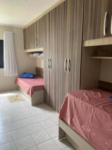 1 Schlafzimmer mit 2 Betten und Holzschränken in der Unterkunft Apartamento beira mar Centro da cidade WiFi grátis in Mongaguá