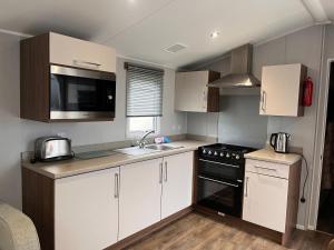 a kitchen with white cabinets and a black stove top oven at Seton Sands Haven Holiday Village in Port Seton