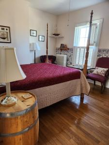 ein Schlafzimmer mit einem Bett und einem Tisch mit einer Lampe in der Unterkunft Louisbourg Harbour Inn in Louisbourg
