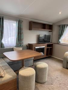a living room with a table and a tv at Seton Sands Haven Holiday Village in Port Seton