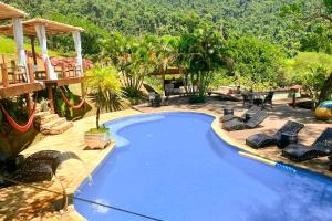 a large blue swimming pool with chairs and a patio at Pousada Sonho Real in Angra dos Reis