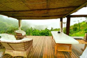 una terraza de madera con sillas de mimbre y una mesa en Pousada Sonho Real en Angra dos Reis