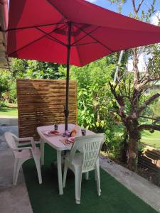 a table with a red umbrella and two chairs at Nature in Fort-de-France