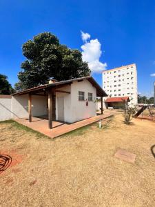 a small white house with a tree and a building at Apartamento 2 quartos mobiliado in Três Lagoas