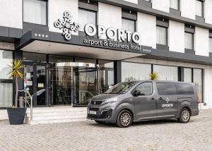 Oporto Airport & Business Hotel في مايا: سيارة فان فضية متوقفة أمام مبنى