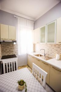 een keuken met witte kasten, een tafel en een wastafel bij Viewpoint Central apartment in Tirana