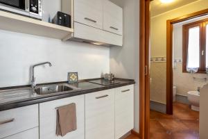 a kitchen with white cabinets and a sink at Sa Domo Apartments in Alghero +21 photos