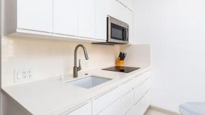 cocina blanca con fregadero y microondas en Condominio 223 El Careyes Club & Residences, en Careyes