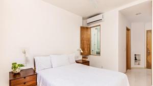 1 dormitorio con cama blanca y espejo en Condominio 223 El Careyes Club & Residences, en Careyes