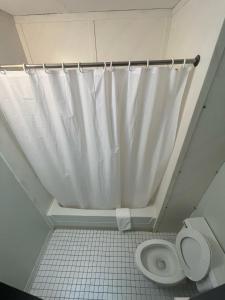 uma casa de banho com uma cortina de chuveiro branca e um WC. em Blackstone Hotel em Mandan