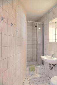 a white tiled bathroom with a shower and a sink at Hotel am Liepnitzsee in Wandlitz