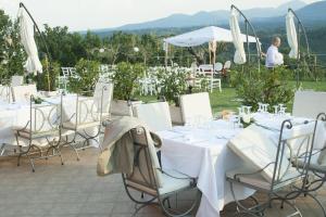 un grupo de mesas y sillas con mesas blancas y sombrillas blancas en Salisù Country House, en Mignano Monte Lungo