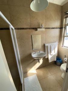 een badkamer met een wastafel, een spiegel en een toilet bij Maerua Mall Luxe Accommodations 3rd Floor in Windhoek