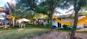 un patio con árboles y una casa con hamaca en chalé na praia da Taiba en São Gonçalo do Amarante