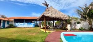 a hut with a hammock and a swimming pool at Portal Vida chalé na praia da Taiba in São Gonçalo do Amarante