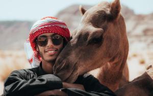 a man is hugging a brown horse at Wadi Rum Desert Dunes Luxury Camp in Wadi Rum
