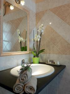 a bathroom sink with a mirror and a towel at CuccuruAio' B&B in Siamaggiore