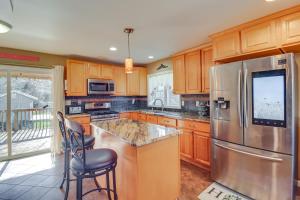 a kitchen with wooden cabinets and a stainless steel refrigerator at Riverfront Kresgeville Getaway Near Blue Mountain! 