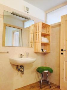 La salle de bains est pourvue d'un lavabo et d'un tabouret vert. dans l'établissement Baita del Beniamino, à Roncegno