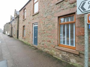 un edificio de ladrillo con una puerta azul en una calle en 16 Main Street, en Ellon