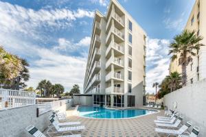 aominium building with a swimming pool and lounge chairs at Seacrest 610 is a 2 BR Gulfside on Okaloosa Island condo in Fort Walton Beach