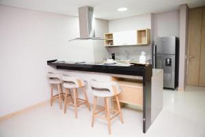 La cuisine est équipée d'un comptoir avec tabourets et d'un réfrigérateur. dans l'établissement Aparta Suite en el BlueGarden, à Barranquilla
