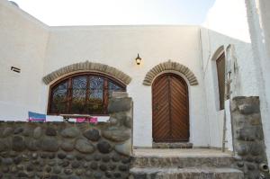 una iglesia con dos puertas y una pared de piedra en The Lady of Flakopi, en Pachaina