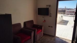 a living room with two chairs and a flat screen tv at Guest House Alam w in Marsa Alam City