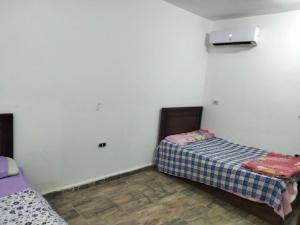 2 Betten in einem kleinen Zimmer mit weißen Wänden in der Unterkunft Guest House Alam w in Marsa Alam City