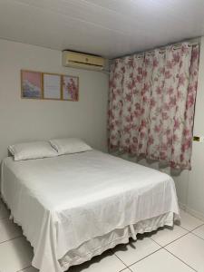 um quarto com uma cama branca e uma janela em Casa c/ piscina e edícula em Foz do Iguaçu