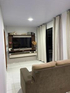 a living room with a couch and a flat screen tv at Casa c/ piscina e edícula in Foz do Iguaçu
