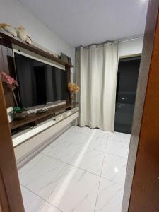 uma sala de estar com uma televisão grande e um piso de azulejo branco em Casa c/ piscina e edícula em Foz do Iguaçu