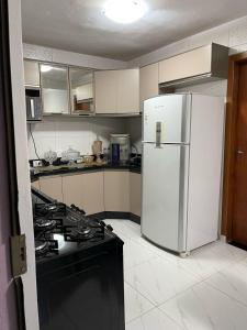 a kitchen with a white refrigerator and a stove at Casa c/ piscina e edícula in Foz do Iguaçu