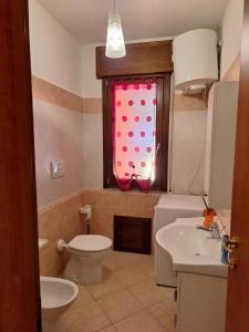 uma casa de banho com um WC, um lavatório e uma janela em Casa Ponente e Casa Levante em Buggerru